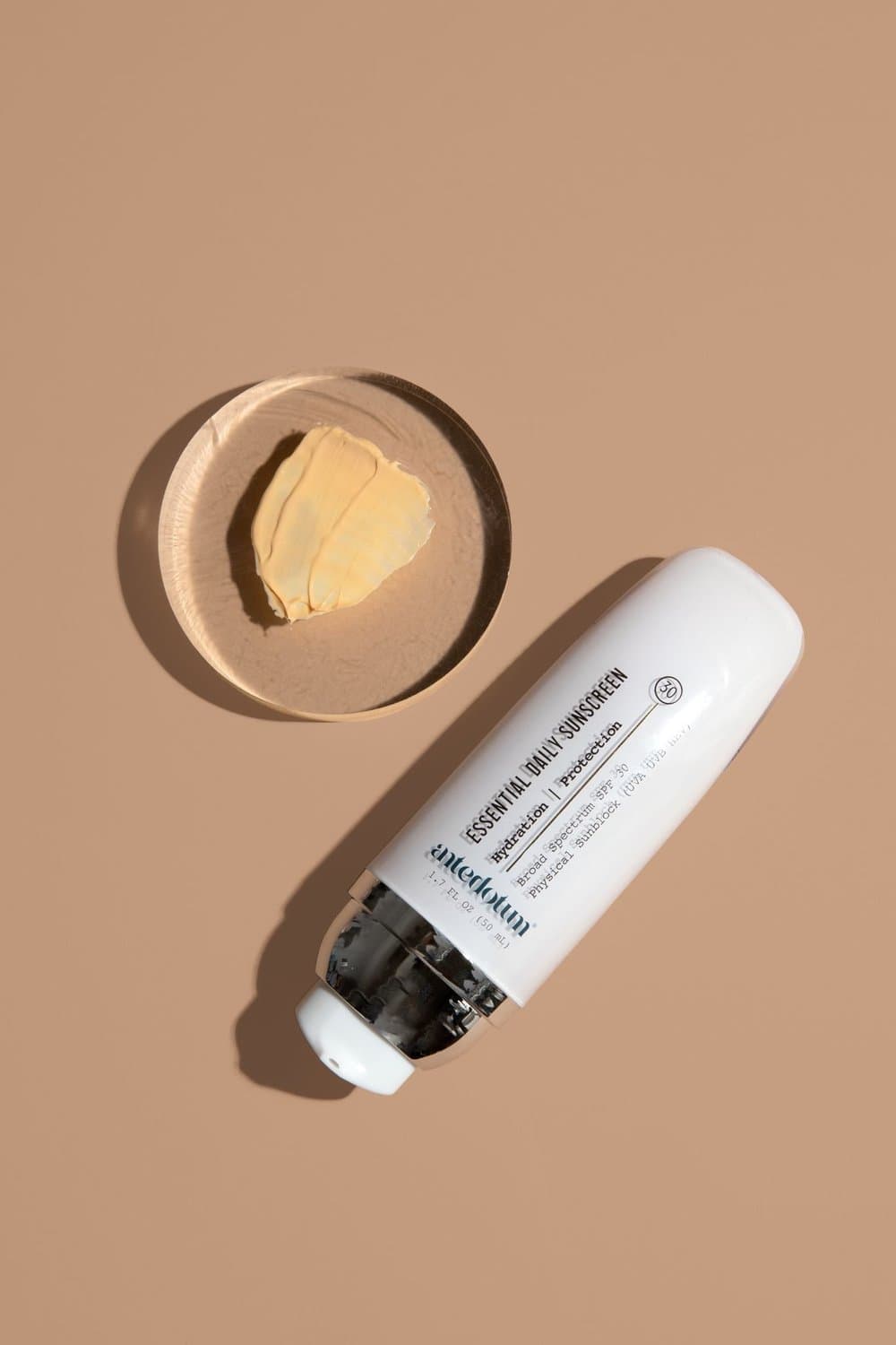 Antedotum sunscreen bottle beside a small dish of shea butter.