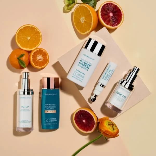 Colorescience skincare products arranged with oranges and a flower.