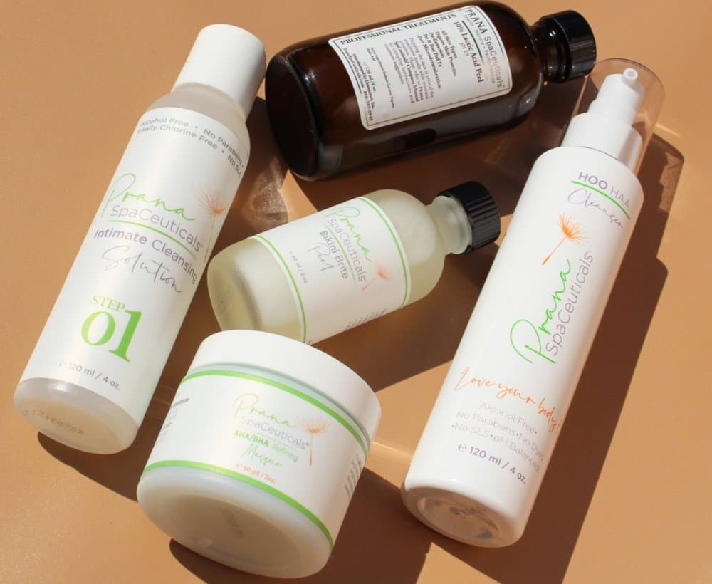 Prana SpaCeuticals skincare and treatment bottles arranged on a tan surface.