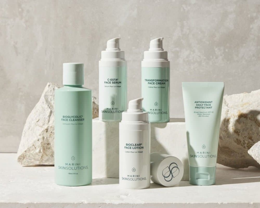Marini Skin Solutions skincare products arranged on white rocks.