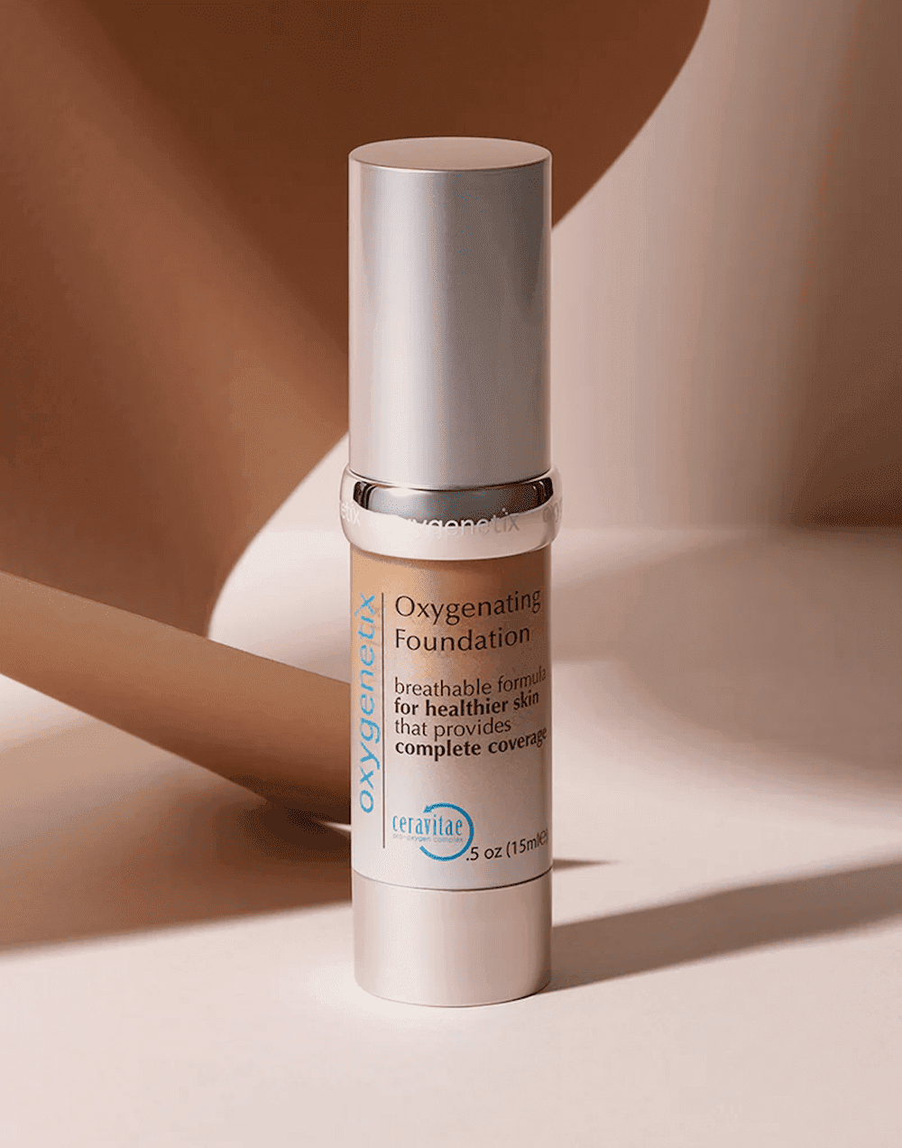 Bronze Oxygenating Foundation bottle with a silver cap on a beige surface.